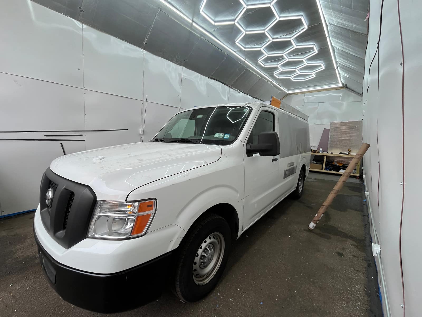 Unwrapped white Nissan NV parked in the NYC Car Wraps shop before work begins