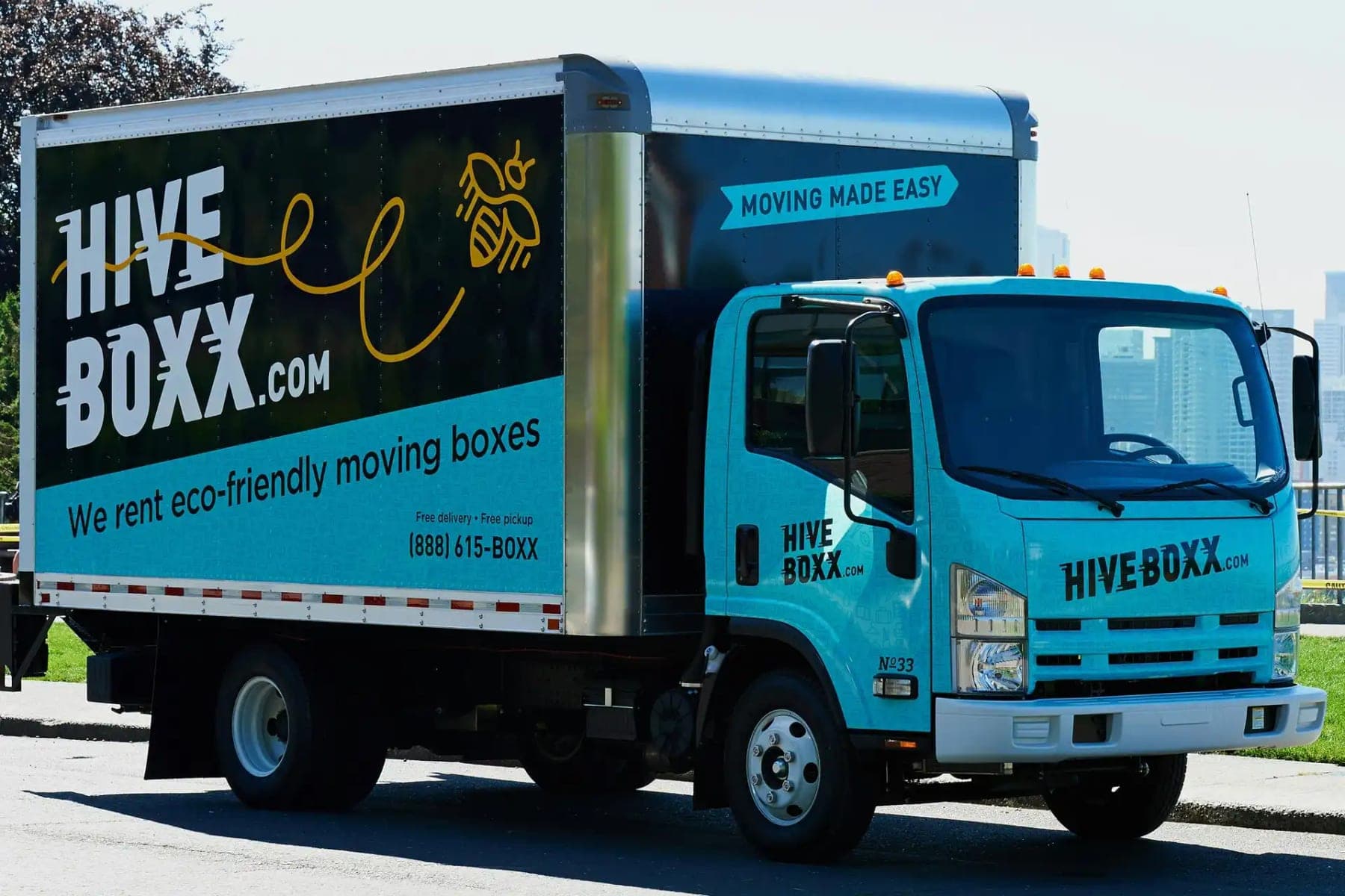 Teal Isuzu box truck for HiveBoxx.com with a printed box graphic and bee illustration, side view