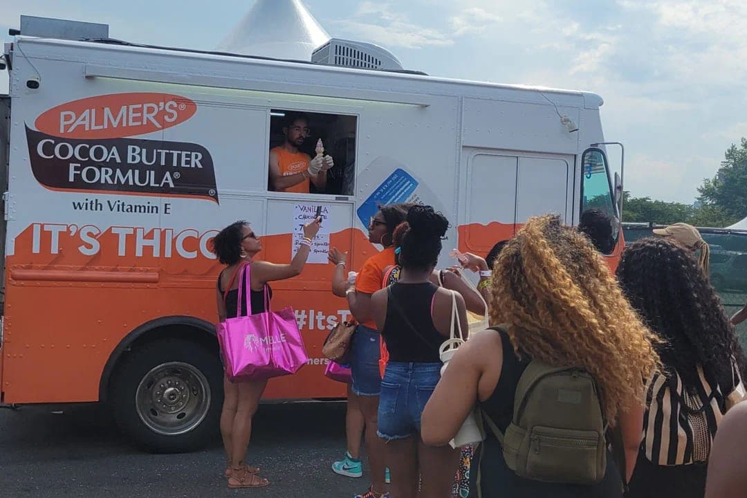 Orange Palmer's Cocoa Butter Formula step van at an outdoor event with a crowd gathered at the serving window