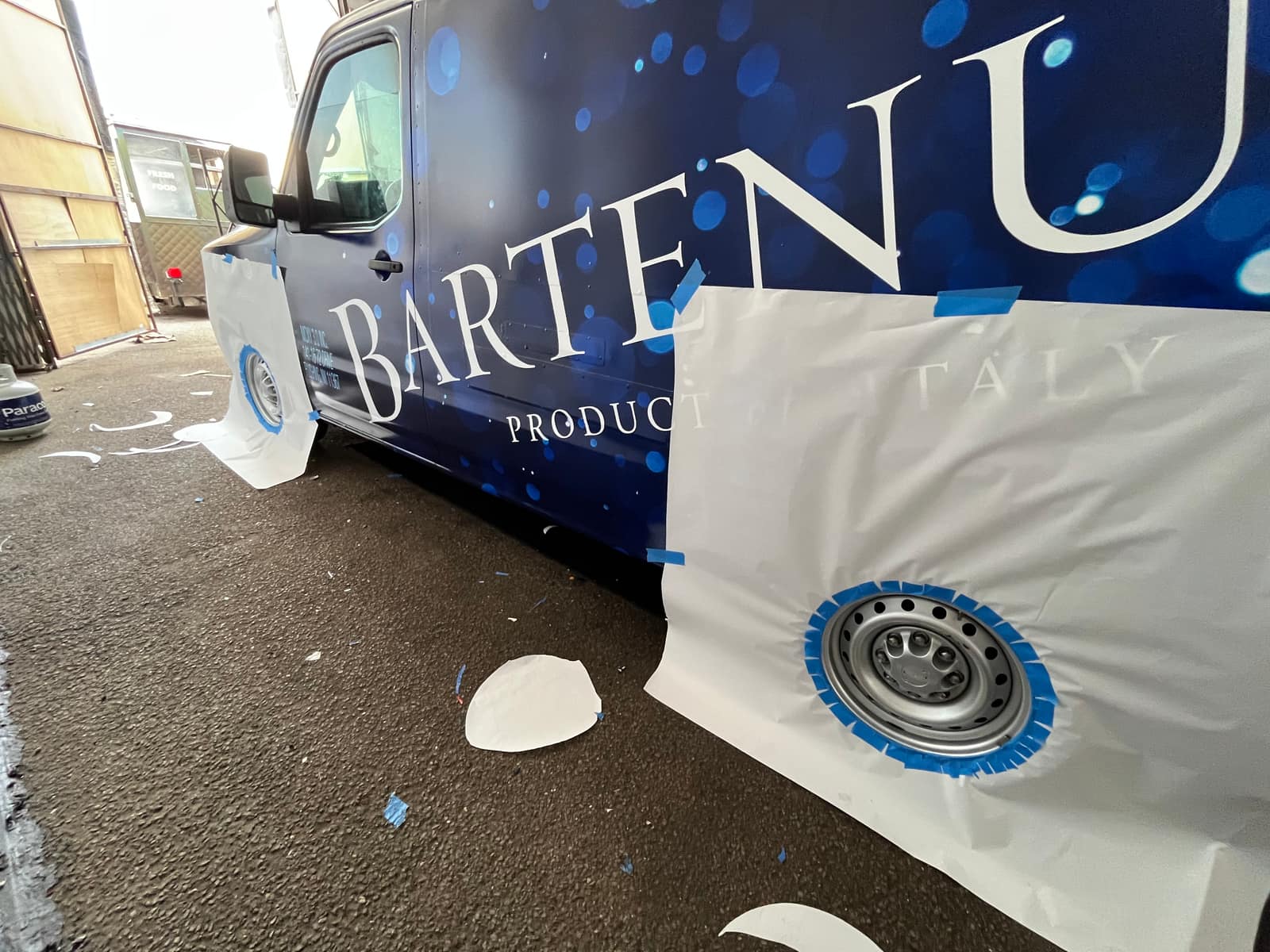 Printed vinyl being applied to a fleet van in the NYC Car Wraps shop